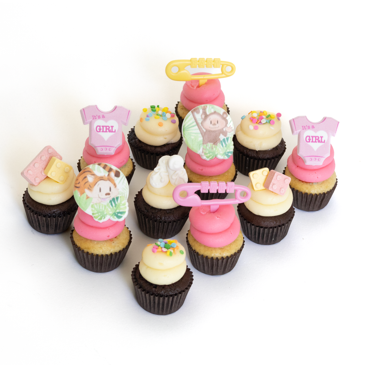 The It's a Girl Dozen 12 pack of nut-free cupcakes with pink and white frosting and baby animal rings for a baby shower in Toronto.	