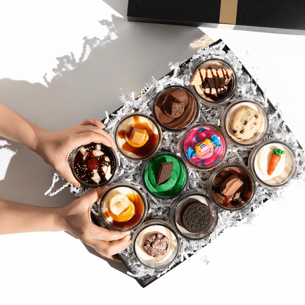 An assortment of 12 Dirty Dozen Jarcakes in clear glass jars featuring gourmet nut-free cupcake flavours like Red Velvet and Oreo for party catering in Toronto.